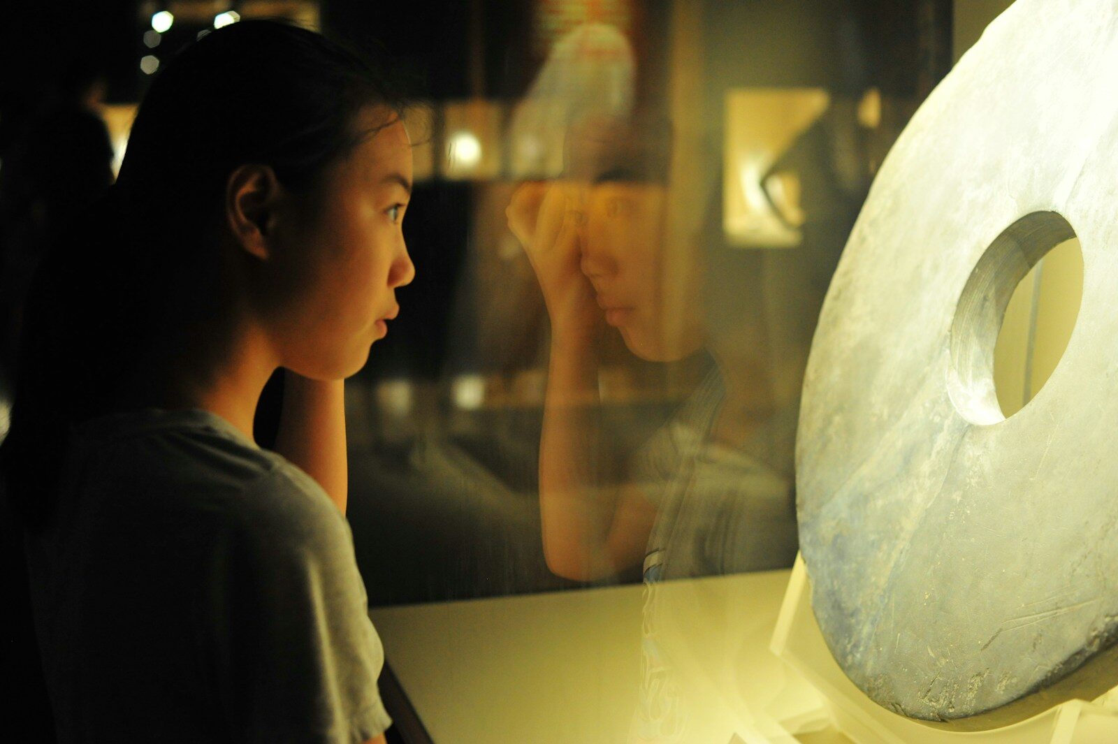 Young woman looks at ancient artifact in museum